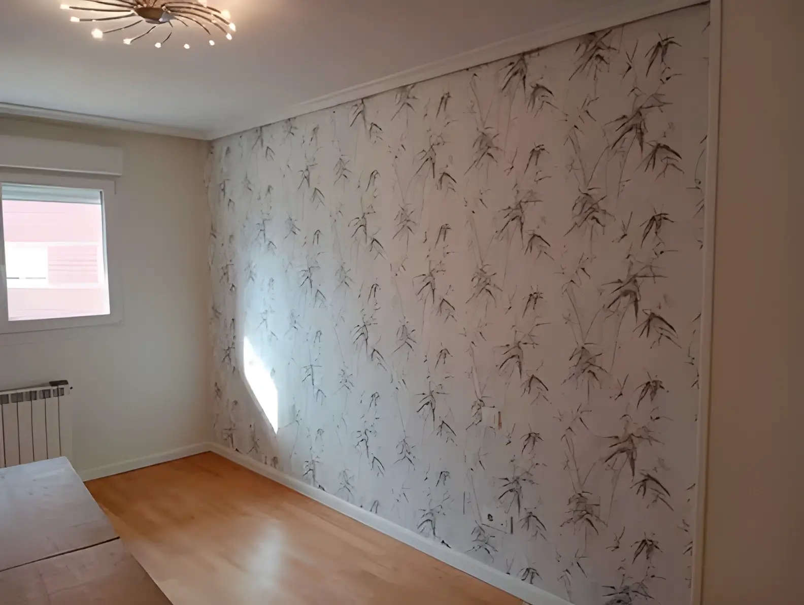 Los pintores Almería colocando papel pintado en pared de acento de habitación luminosa